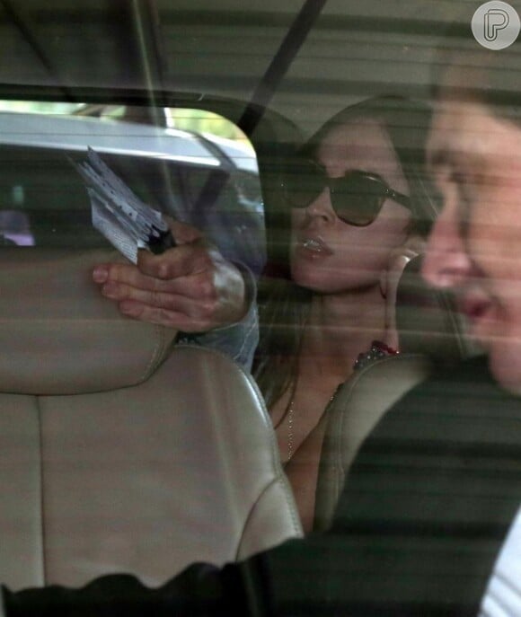 Megan sentou no banco de trás do carro, enquanto Brian entrava com o filho do casal