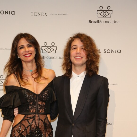 Ao lado do filho Lucas Jagger, ela mostra os detalhes do look cheio de recortes e transparências