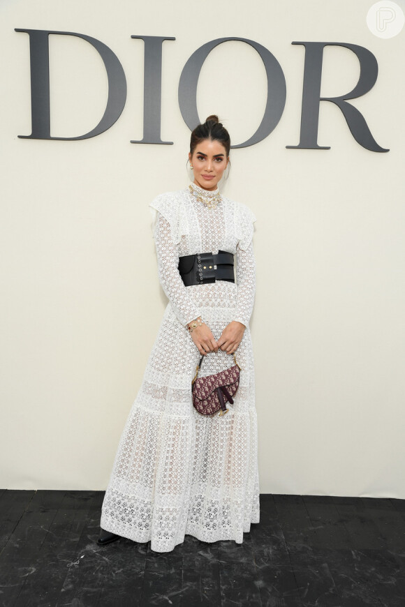 Para assistir ao desfile de Christian Dior, em Paris, a blogueira Camila Coelho apostou em um vestido longo branco rendado com o cinto largo preto da grife