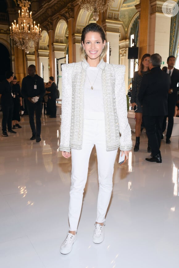 No desfile da Balmain, na Semana de Moda de Paris, Helena Bordon elegeu um look de t-shirt e calça branca simples com um terno todo elaborado de pérolas por cima