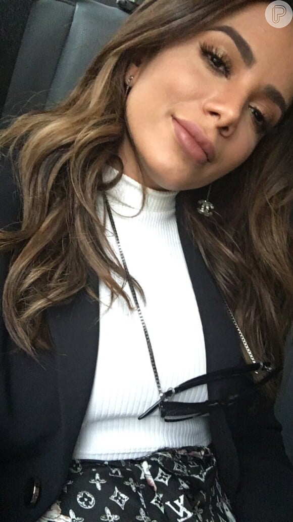 Anitta completou a produção com cropped canelado branco, blazer preto e brinco Chanel