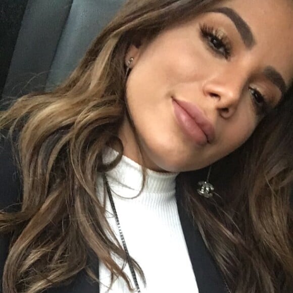 Anitta completou a produção com cropped canelado branco, blazer preto e brinco Chanel