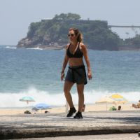 Adriana Esteves caminha de top e short em orla de praia. Fotos!