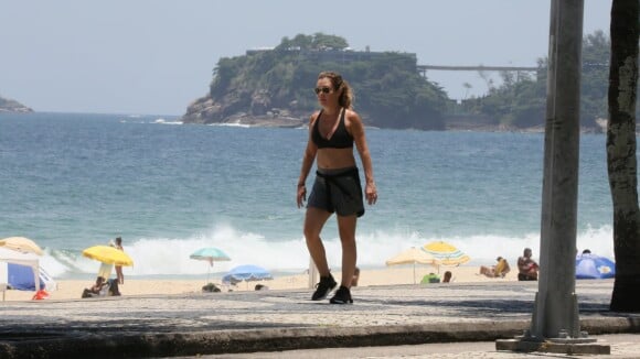 Adriana Esteves caminha de top e short em orla de praia. Fotos!