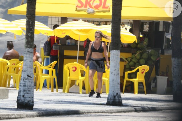 Adriana Esteves caminha de top e short em orla de praia de São Conrado