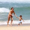 Leticia Birkheuer corre com o filho, João Guilherme, na praia