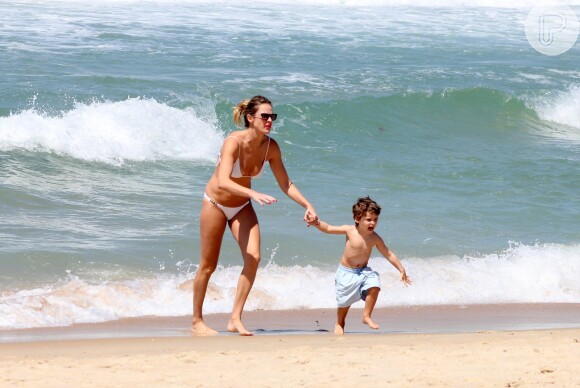 Leticia Birkheuer corre com o filho, João Guilherme, na praia