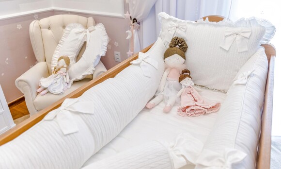 O enxolval é todo em tons de branco com bonecas de pano para enfeitar a cama e o berço