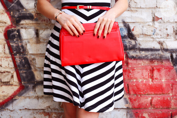Combine a bolsa vermelha com peças de tons neutros, como o vestido ou a saia em preto e branco