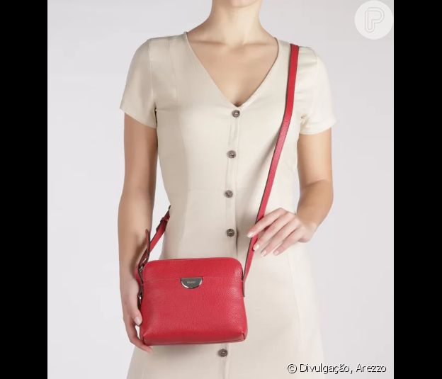 A bolsa vermelha, com alça tiracolo, traz o mood do Natal ao look