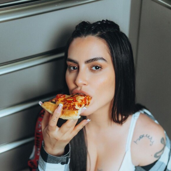 Cleo comendo uma fatia de pizza em foto postada no seu Instagram