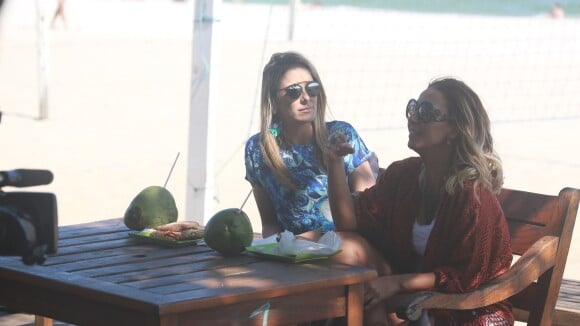 Ticiane Pinheiro bebe água de coco e come sanduíche durante gravação na praia