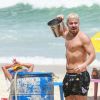 Thiago Martins se refresca ao pegar água do mar com balde na praia da Barra da Tijuca, zona oeste do Rio de Janeiro