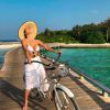 Deborah Secco investiu em biquíni clássico branco e pareô branca para passeio de bike entre os bangalôs de resort nas Maldivas