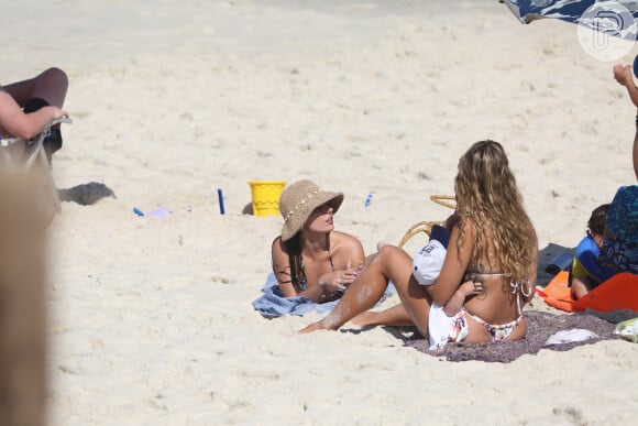 Isis Valverde toma sol em dia de praia com amiga e filho