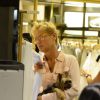 Com o mascote nos braços, Xuxa vê roupa em loja de shopping no Rio