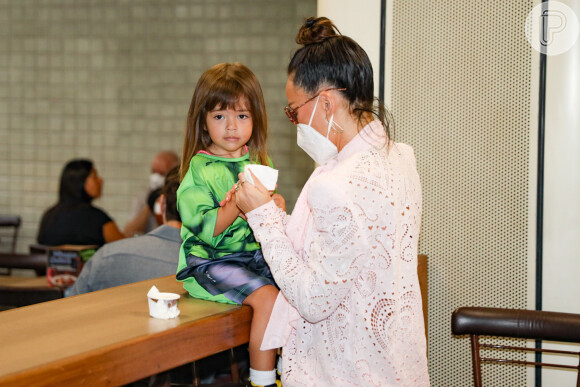 Sabrina Sato ajuda a filha, Zoe, a comer sorvete em aeroporto