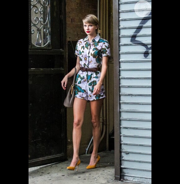 Para um passeio, Taylor Swift usou um macaquinho floral combinado com um scarpin amarelo e um cinto de couro marcando a cintura