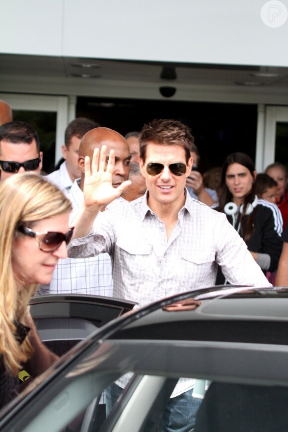 Tom acena para os fotógrafos ao desembarcar no Brasil em dezembro de 2011