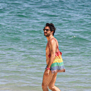 Caio Blat deixou praia com uma bolsa com as cores do arco-íris