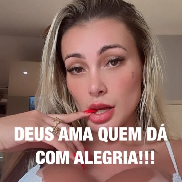 Andressa Urach sensualiza de calcinha e sutiã e exibe a língua bifurcada. A frase 'Deus ama quem dá com alegria!' ilustra o vídeo