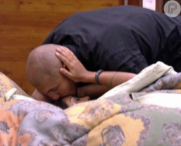 Carinhoso, Fernando dá beijo na testa de Amanda, deitada na cama do quarto do Líder