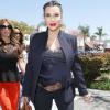 Mesmo com um look mais justinho e formal, Kim Kardashian usou uma blusa de seda com rendas que mostrava sua barriguinha