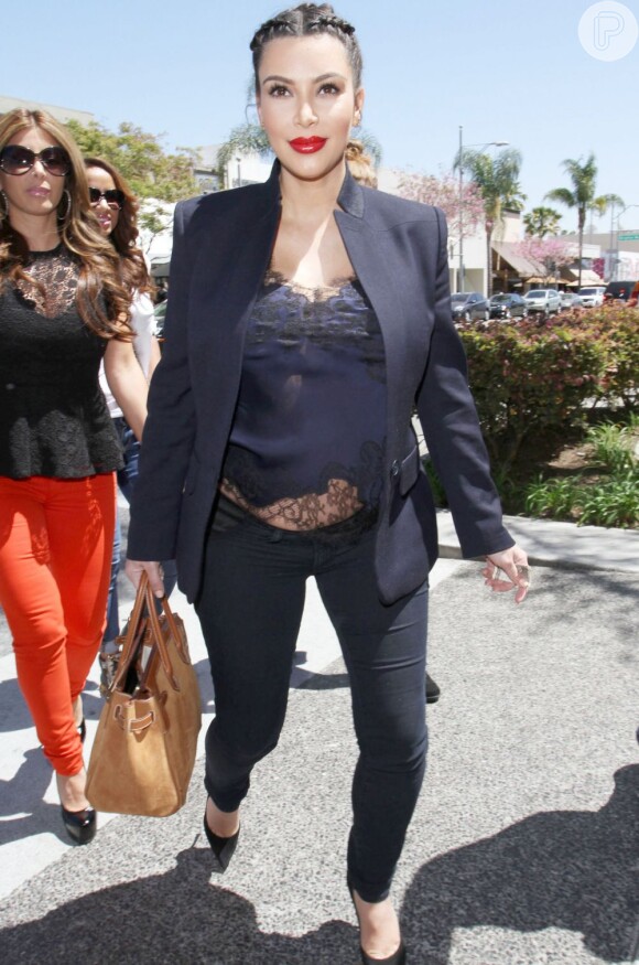 Mesmo com um look mais justinho e formal, Kim Kardashian usou uma blusa de seda com rendas que mostrava sua barriguinha