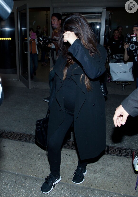 Kim Kardashian coloca a mão no rosto para evitar os flashes