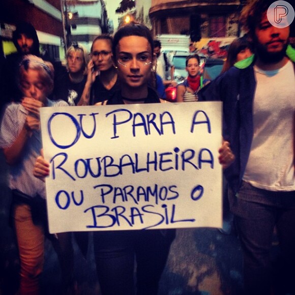 Thaila Ayla posa nas ruas segurando um cartaz com palavras de ordem durante protesto contra o aumento das passagens no Rio de Janeiro