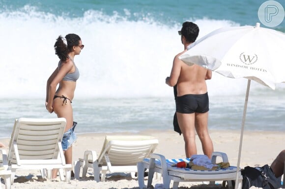 A atriz usou cabelo preso por causa do calor e do vento que faziam na praia da Barra