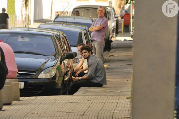 Caio Castro lancha sentado na calçada, antes de gravar cenas para 'Amor à Vida'
