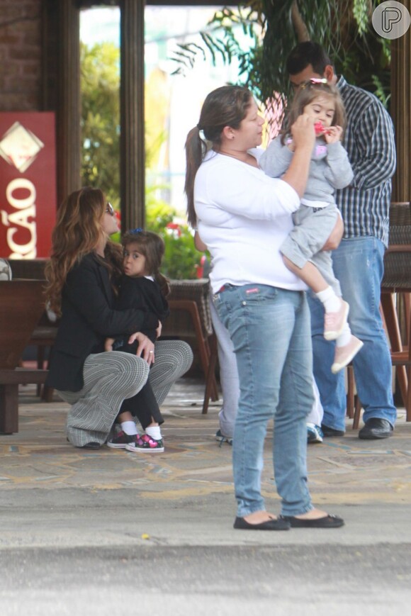Giovanna Antonelli carrega uma de suas filhas e a babá brinca com a outra