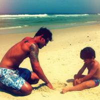 Juliano Cazarré se diverte com o filho na areia da praia