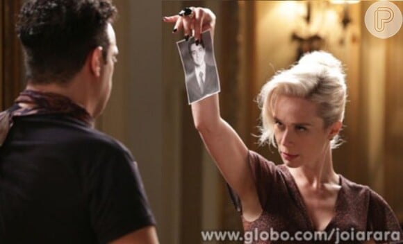 Aurora Lincoln (Mariana Ximenes) mostra a foto de Décio (Miguel Rômulo) e garante que ele vai lhe pagar o dinheiro que lhe deve, em 'Joia Rara'