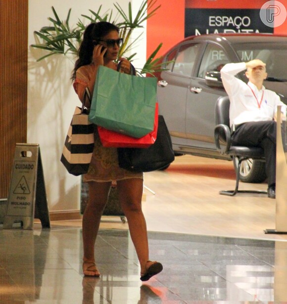 Juliana Paes fala no celular e carrega compras