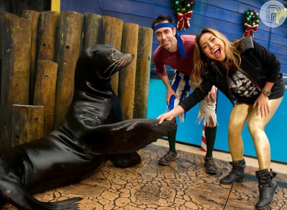 Sabrina Sato aperta a mão do leão marinho Clyde, em registro feito no SeaWorld, na Flórida, em janeiro de 2013