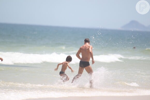Daniel de Oliveira e seu filho, Raul, de 5 anos, brincam no mar da praia da Barra da Tijuca, Zona Oeste do Rio de Janeiro