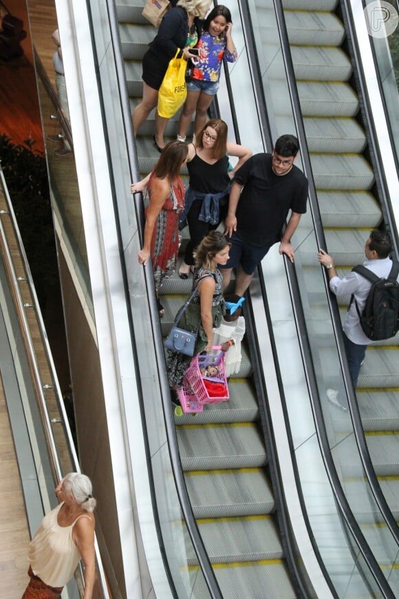 Giovanna Ewbank segura a filha ao descer por escada rolante no shopping
