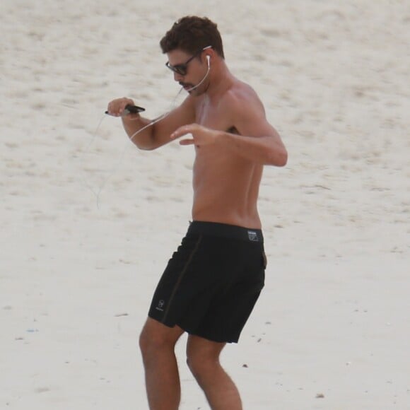 Cauã Reymond fez exercícios pela areia da praia enquanto esperava a namorada, Mariana Goldfarb