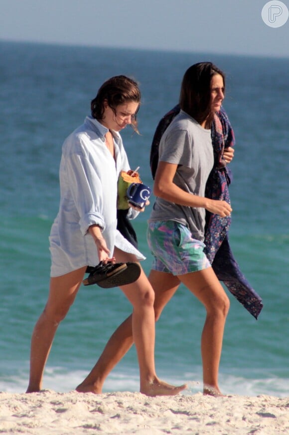 Bruna Linzmeyer se hidrata com água de coco enquanto passeia na praia com a namorada