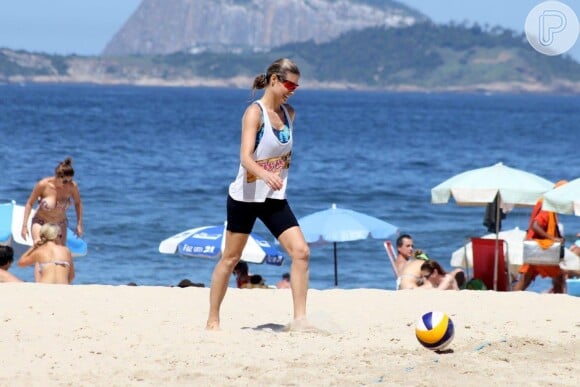 Fernanda Lima usa blusa larga, top e bermuda justa em praia