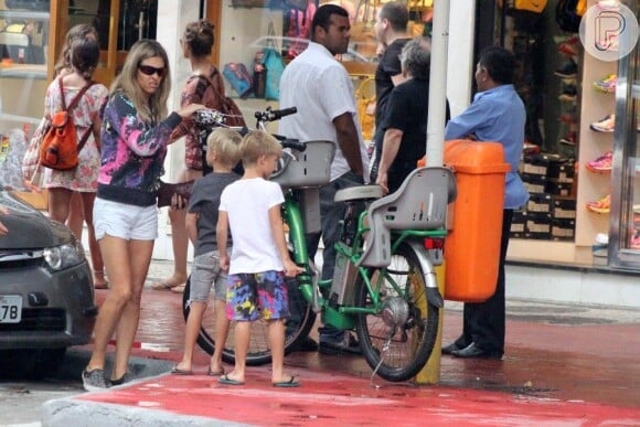 Fernanda Lima leva filho na garupa da bicicleta e faz compras em rua de Ipanema, no Rio em tarde de chuva