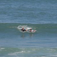 Juliano Cazarré surfa com a mulher e troca beijos na praia da Macumba, no Rio