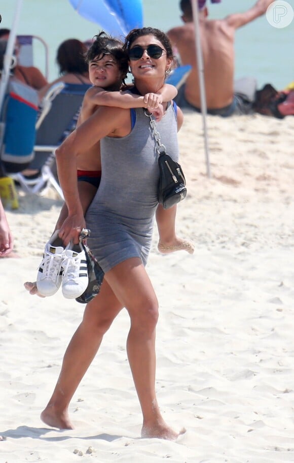 Juliana Paes deixou a praia com o filho caçula, Antônio, na garupa