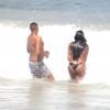 Ludmilla, com biquíni preto fio dental, entra na água com amigo na praia de Copacabana