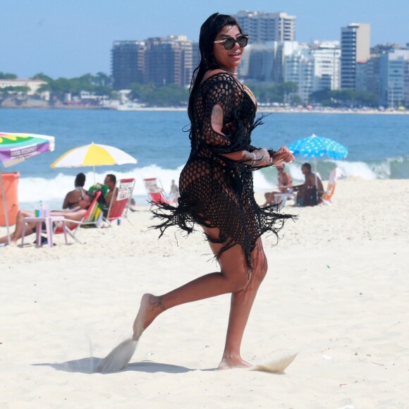 Ludmilla caminha na praia de Copabacana e nota que está sendo fotografada