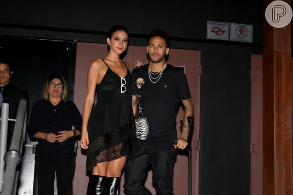 Bruna Marquezine investiu em um vestido curto preto com toque de transparência e botas over the knee de látex para a festa de Rafaella Santos