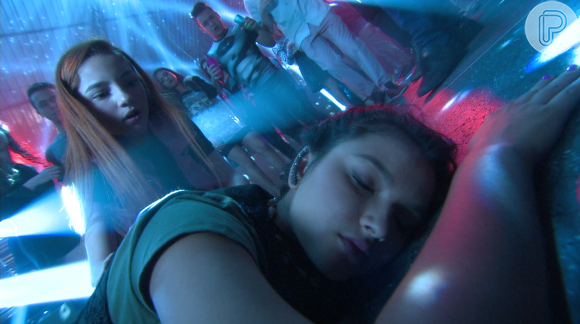 Bruna (Duna Matte) tenta ajudar Cassandra (Bárbara Maia), desmaiada na pista de dança da festa, na novela 'Carinha de Anjo'