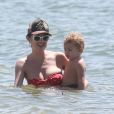 Com o filho no colo, Candice Swanepoel  se protegeu do sol com óculos escuros e boné 